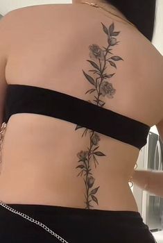 the back of a woman's body with flowers on it and chains around her waist