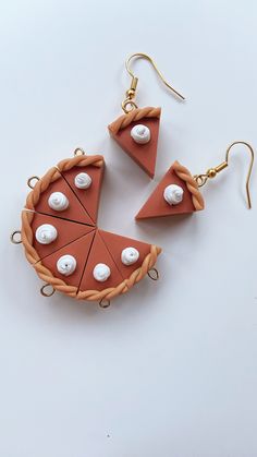 two pieces of pizza are hanging from earwires with pearls on the top and bottom