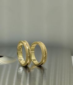 two gold wedding rings sitting on top of a table