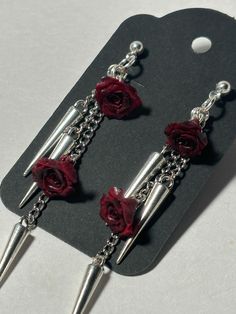 Elevate your gothic accessory collection with these Handmade Rose Spike Dangling Earring, featuring a striking design of silver spikes adorned with vibrant red (or black) roses. Each pair is meticulously crafted to combine edgy elegance with a touch of floral beauty, making them a perfect statement piece for any occasion. The unique blend of materials ensures durability while offering a lightweight feel, allowing for more comfortable wear throughout the day. Alternative Style Silver Party Earrings, Edgy Red Earrings As Gift, Edgy Red Earrings For Gift, Edgy Red Earrings For Gifts, Gothic Metal Earrings For Alternative Fashion, Gothic Hypoallergenic Dangle Jewelry, Nickel-free Gothic Earrings For Festivals, Gothic Nickel-free Earrings For Alternative Fashion, Goth Rose Earrings