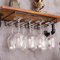 four wine glasses hanging from a shelf on the wall