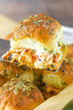 a close up of a sandwich being held by a spatula over some bread rolls