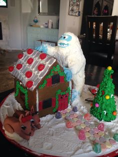 a decorated gingerbread house with an iceman and reindeer on the front, surrounded by christmas decorations