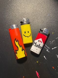 three lighters with faces drawn on them are sitting on the table next to each other