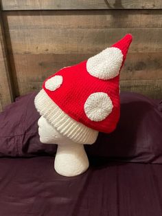 a red and white knitted mushroom hat sitting on top of a head