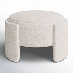 a white ottoman sitting on top of a floor next to a table with two legs