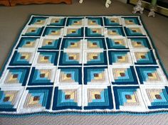 a blue and white quilt on the floor next to a teddy bear in a crib