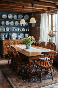 a dining room table and chairs with plates on the wall behind it, in front of a window