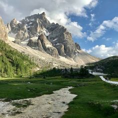 the mountains are covered in snow and green grass, with a stream running between them