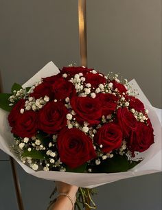 a bouquet of red roses in someone's hand