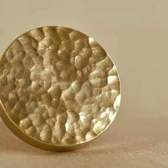 a gold plate sitting on top of a beige table cloth next to a white wall