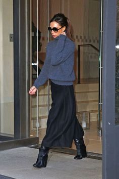 a woman in black boots is walking out of a building