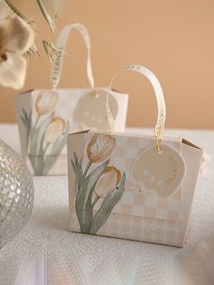 two small bags with flowers painted on them sitting on a table next to a vase