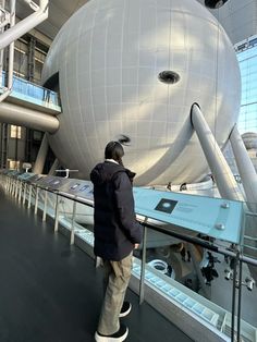 a man standing in front of a large white ball on top of a metal rail