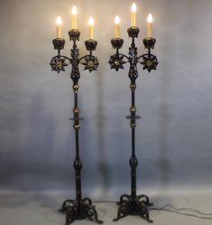 two metal candlesticks sitting next to each other on top of a white table