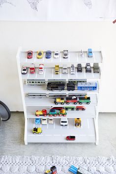 toy cars and trucks are displayed on a white shelving unit in a child's playroom