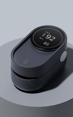 an electronic device with a clock displayed on the front and back side, sitting on a round surface