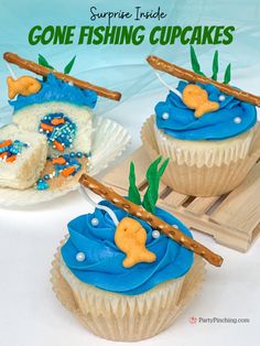 three cupcakes with blue frosting and gold fish on them