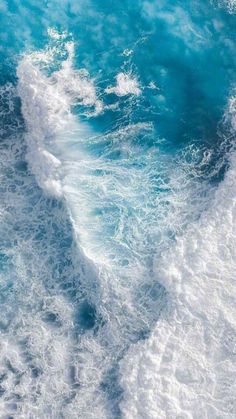 an aerial view of the ocean with waves and foamy blue water in the foreground