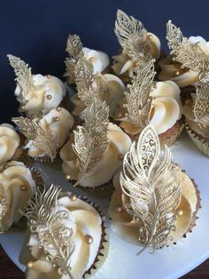 cupcakes decorated with gold leaf decorations on a white plate