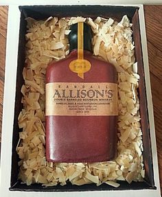 an empty bottle in a box with wood shavings