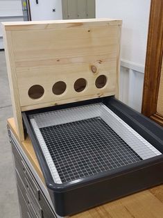 a wooden box with holes in it on top of a wood table next to a mirror