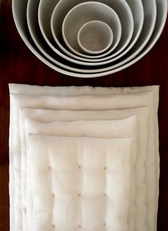 a stack of white plates and bowls on top of a wooden table