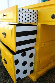 a yellow dresser with black and white polka dots on it's drawers is sitting in the grass