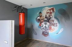 a room with a boxing mural on the wall and a punching bag in the corner