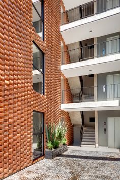 an apartment building with brick walls and balconies on the outside, as well as plants