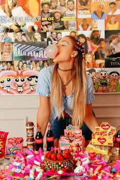 a woman blowing bubbles over a table full of candy and candies, with pictures on the wall behind her