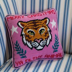 a pink tiger pillow sitting on top of a blue and white striped couch next to a wall