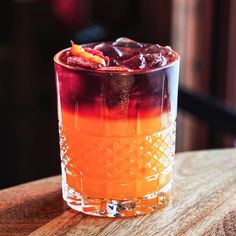 an orange and red drink sitting on top of a wooden table