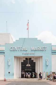 people are standing in front of the central market building with an american flag on top