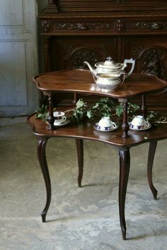 a wooden table with two tiered trays holding tea cups and saucers on it