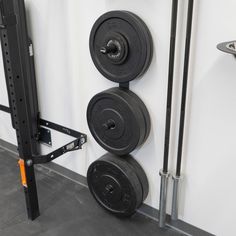 two black barbells mounted to the side of a white wall with metal bars