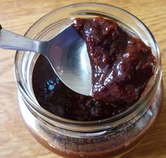 a spoon is in a jar filled with chocolate sauce on a wooden table top,