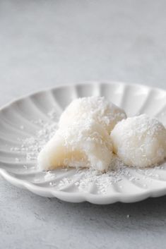 two desserts on a white plate with sugar sprinkled around them, sitting on a table