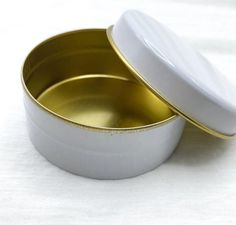 two white and gold tins sitting on top of each other