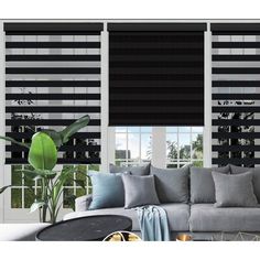 the living room is decorated with black and white striped blinds, grey couches, and large windows