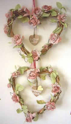 two heart shaped wreaths with flowers and hearts hanging on the wall next to each other