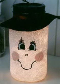 a glass jar with a face drawn on it's side and a black lid