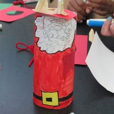 a child's hand is holding a pencil and drawing on a paper tube with santa claus