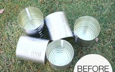 four empty tin cans sitting on top of green grass