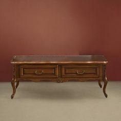 a wooden table with two drawers on it's sides and a red wall in the background