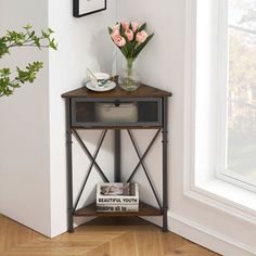 a vase with flowers on top of a wooden table next to a white wall and window