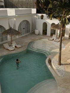 a person swimming in a pool next to some palm trees