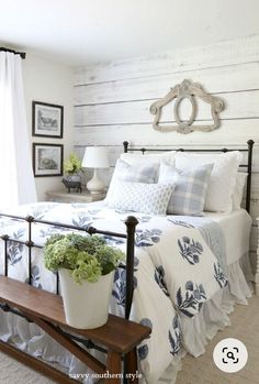 a white bed with blue and white comforter in a bedroom next to a window