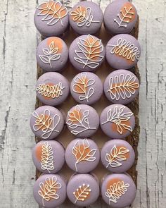 purple and orange decorated rocks sitting on top of a piece of wooden plank with leaves painted on them