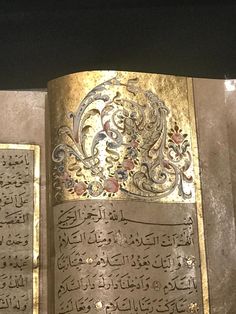 an open book with arabic writing on the cover and gold foiled paper covering it